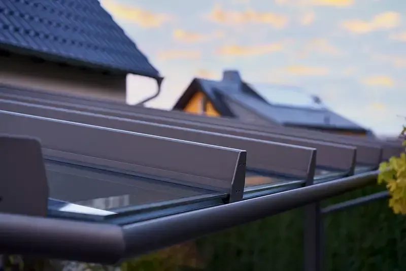 Eine Nahaufnahme eines Daches mit einem Glasdach und einem Haus im Hintergrund.