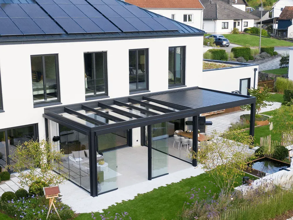 Eine Luftaufnahme eines Hauses mit einer Pergola und Solarmodulen auf dem Dach.