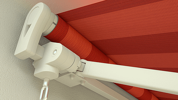 An einer Wand ist eine rot-weiß gestreifte Markise angebracht.