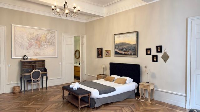 Chambre avec lit, œuvres d'art, puits de lumière et rangements intégrés. Éclairage doux et chaleureux.