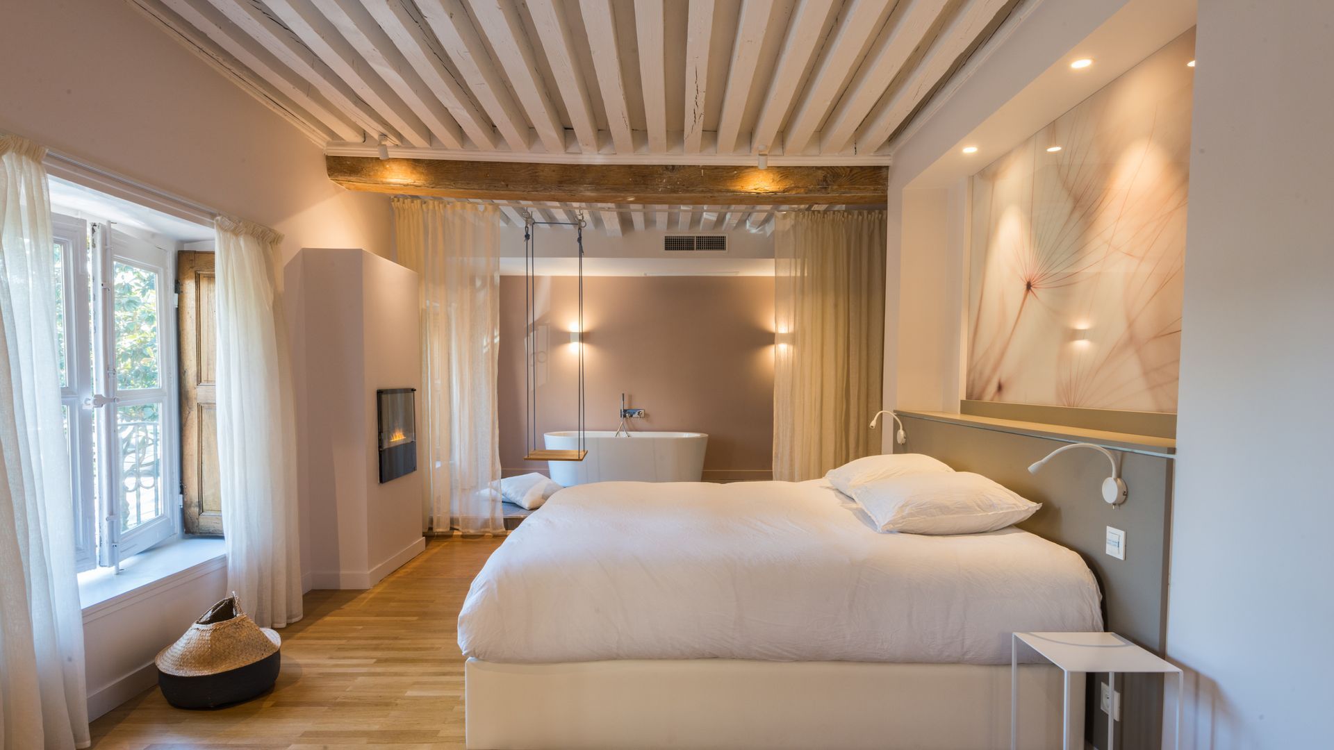 Chambre moderne et lumineuse avec lits jumeaux, plafond en bois, grandes fenêtres et décoration aux tons neutres et doux