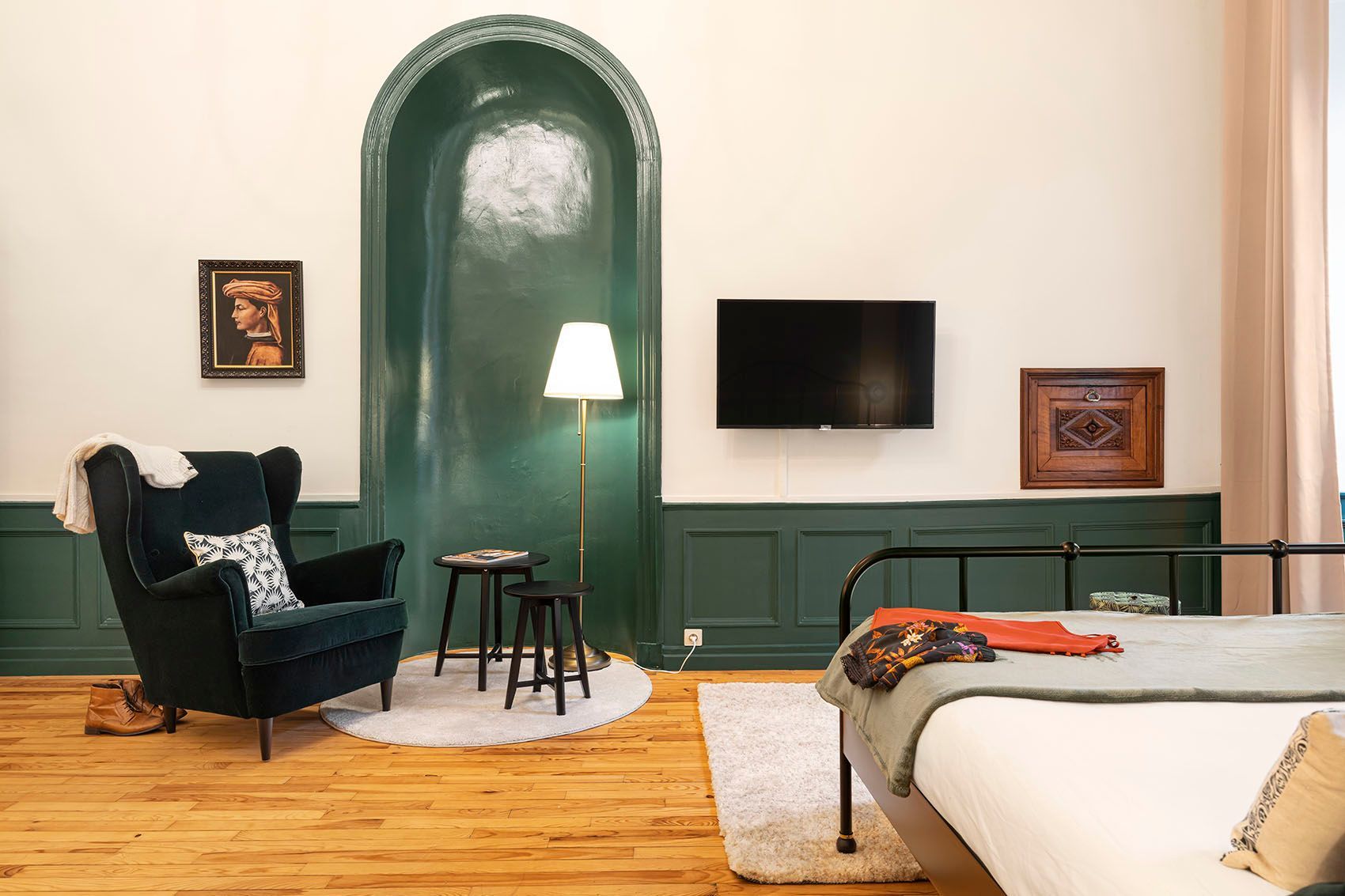 Chambre avec poutres apparentes, tapisserie, lit, table ronde et touches dorées.