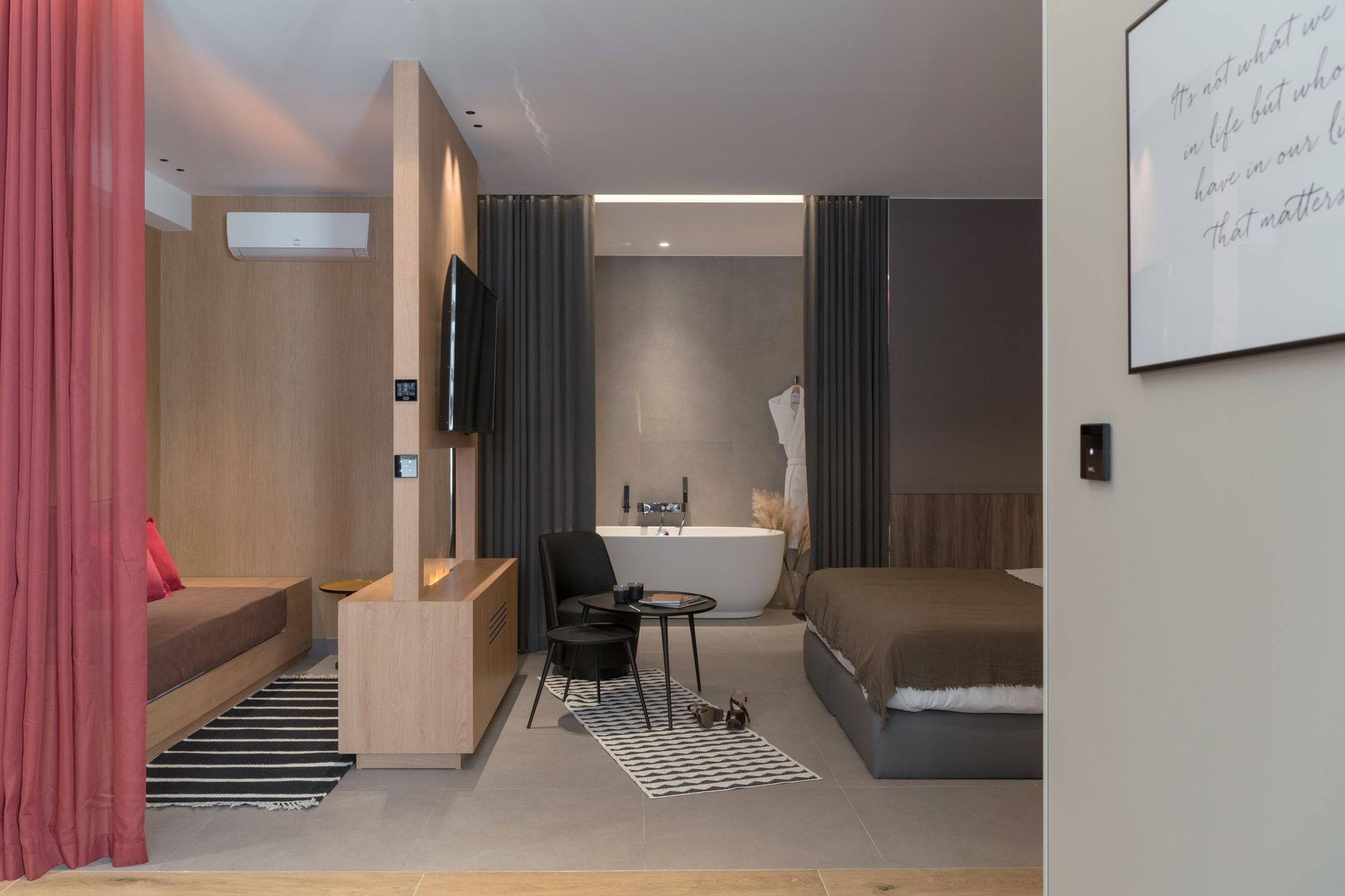 Chambre d'hôtel moderne avec lit, coin salon, bureau et éléments en bois chaleureux.