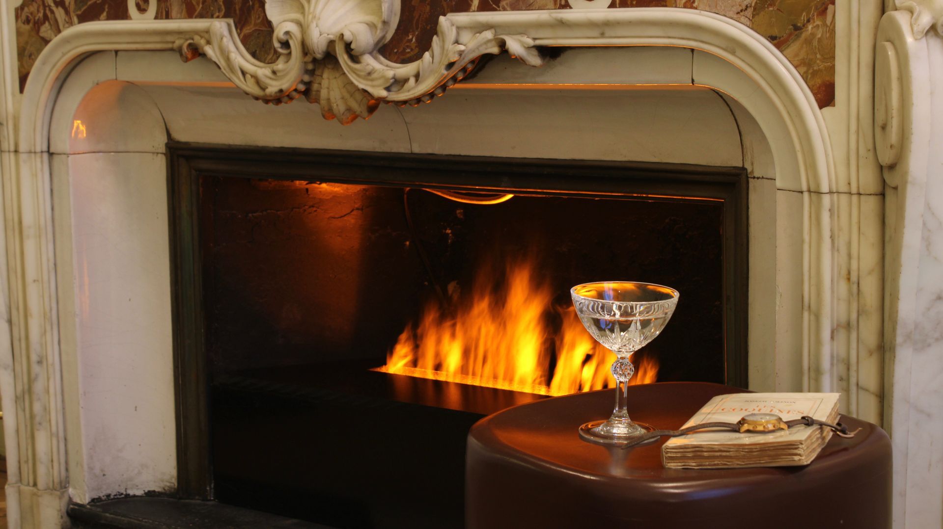 Cheminée élégante avec un feu crépitant, petite table, verre à martini et livre dans une pièce confortable