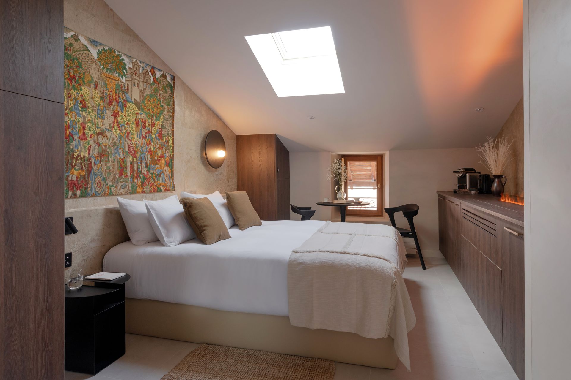 Chambre avec lit, œuvres d'art, puits de lumière et rangements intégrés. Éclairage doux et chaleureux.