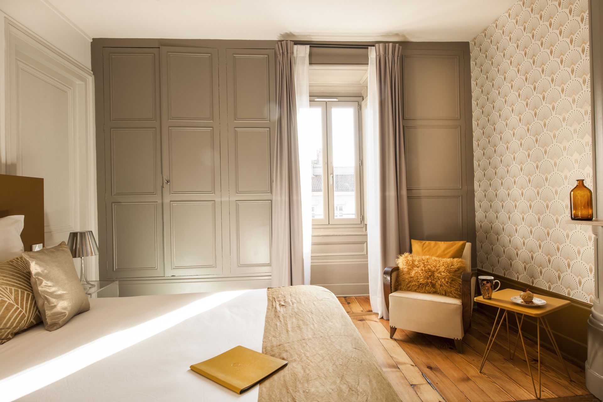 Salle de bains moderne avec baignoire, miroir rond et deux douches ; carrelage beige.