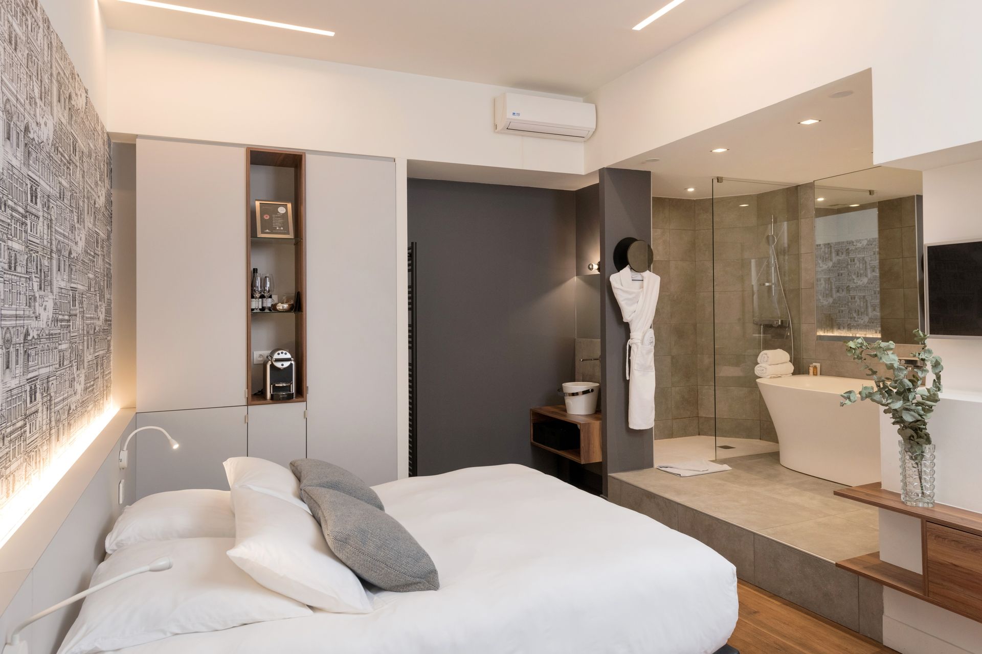 Salle de bains luxueuse avec baignoire îlot, chaise longue rouge et œuvres d'art sur les murs roses.