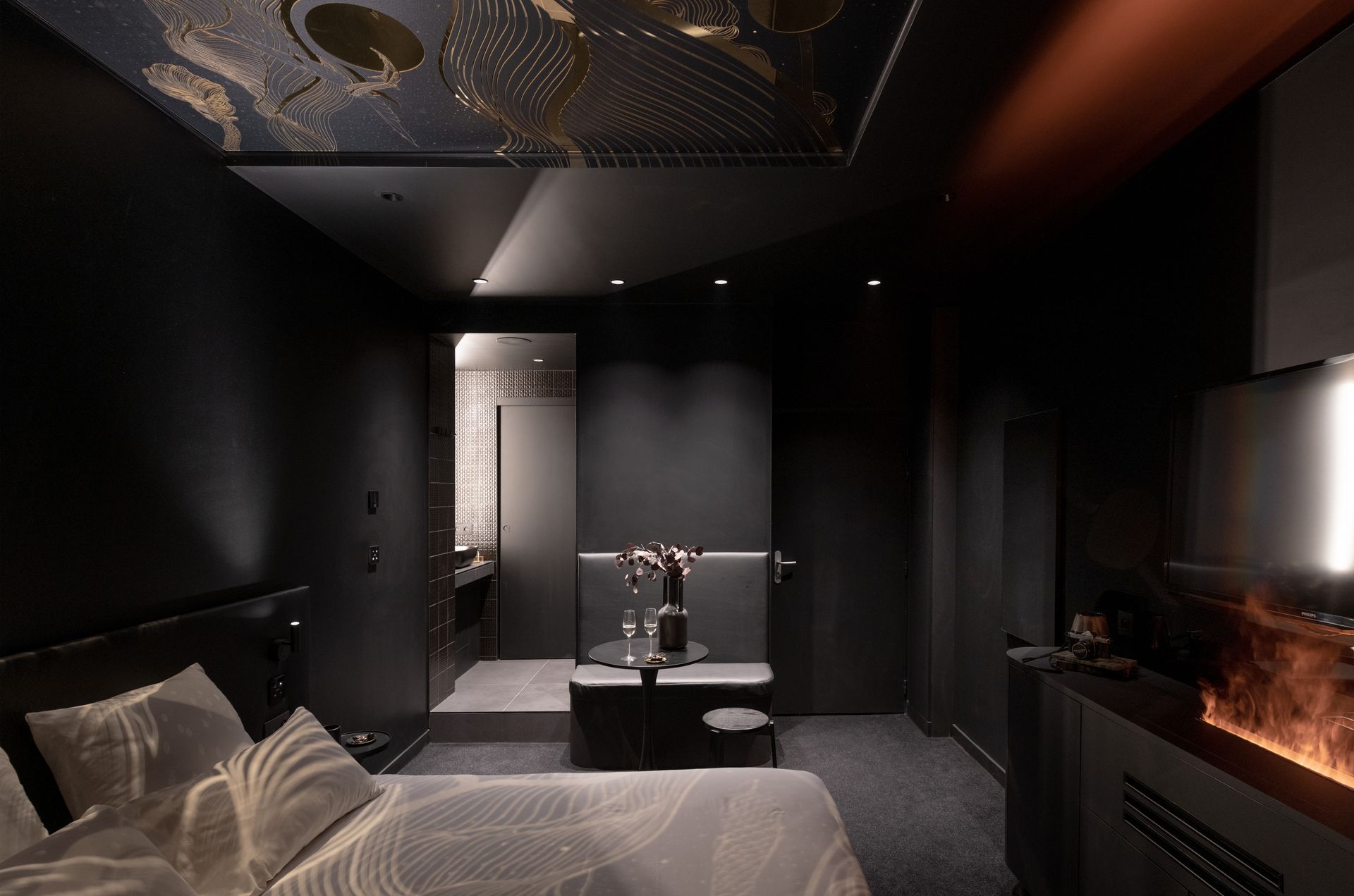 Salle de bains luxueuse avec baignoire îlot, chaise longue rouge et œuvres d'art sur les murs roses.
