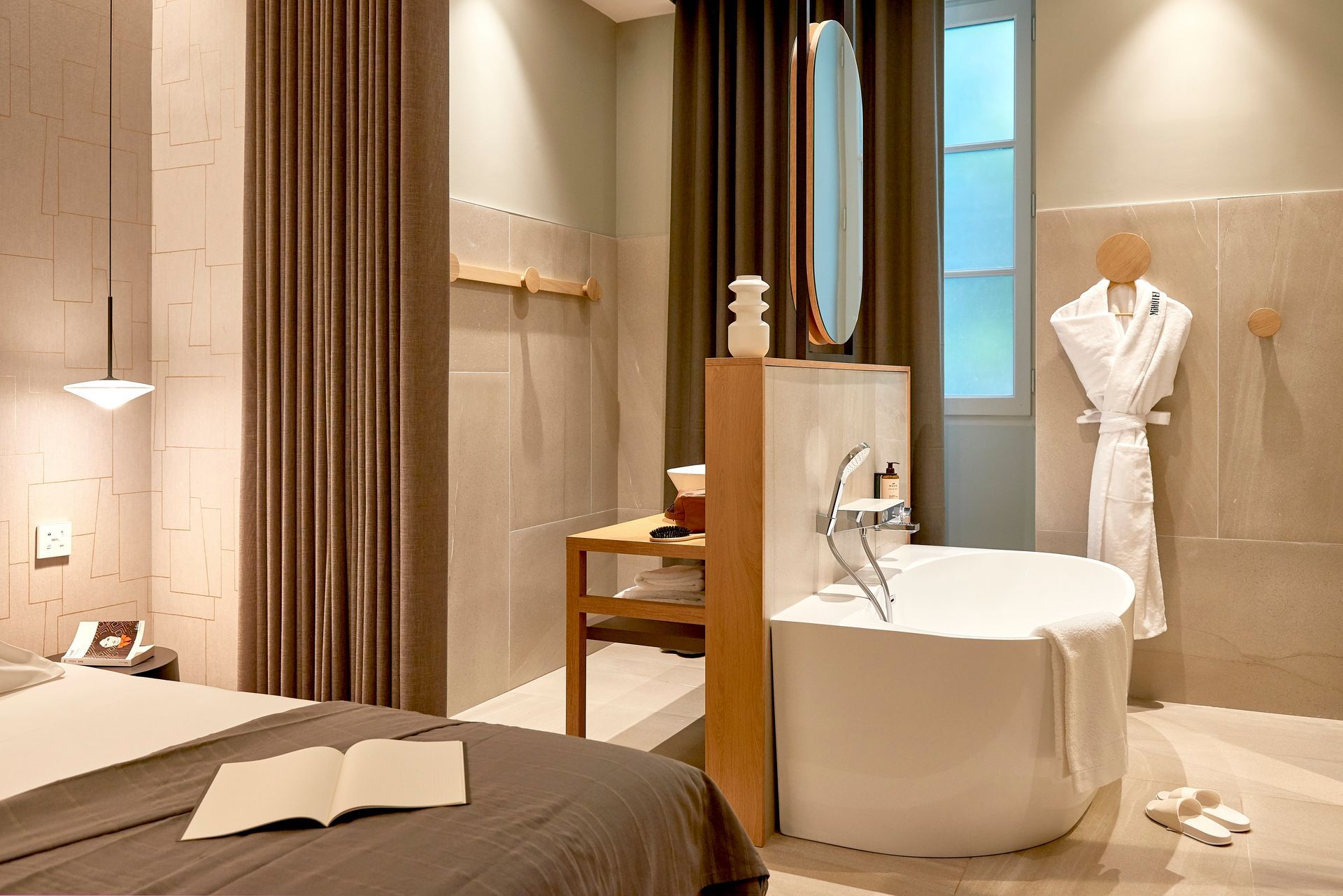 Chambre d'hôtel moderne avec baignoire, lit et tons neutres.
