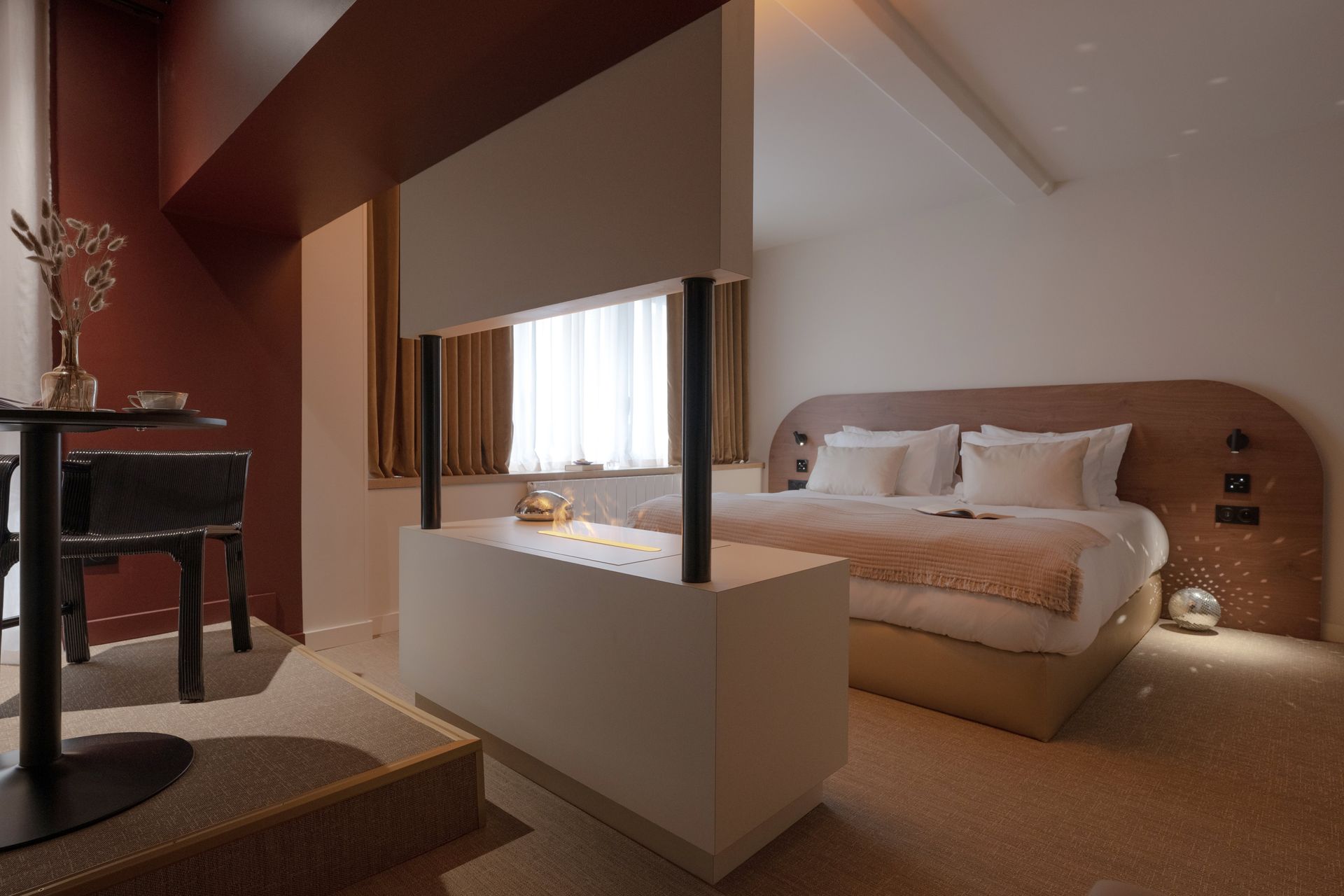 Salle de bains luxueuse avec baignoire îlot, chaise longue rouge et œuvres d'art sur les murs roses.