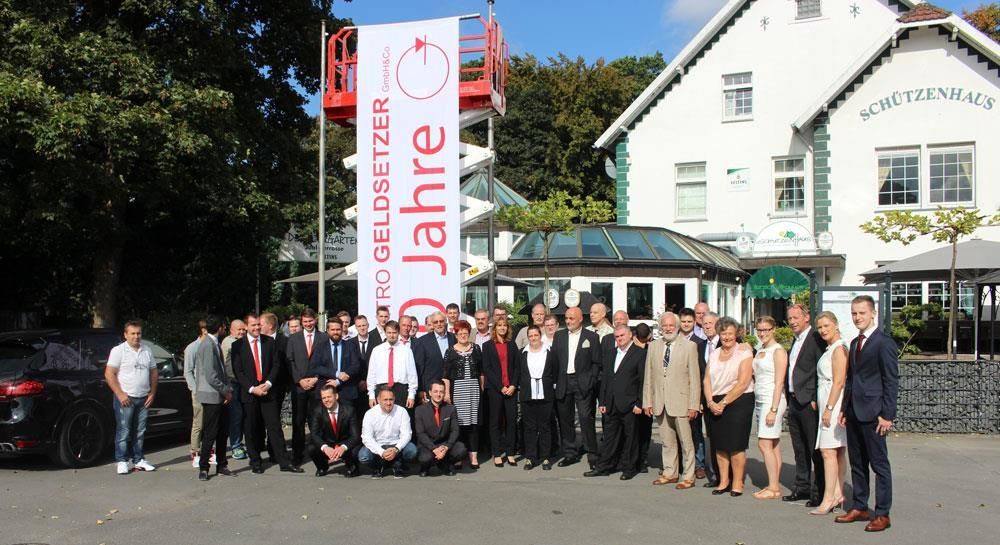 Eine Gruppe von Menschen steht vor einem Gebäude mit einem Banner mit der Aufschrift „Jahre“