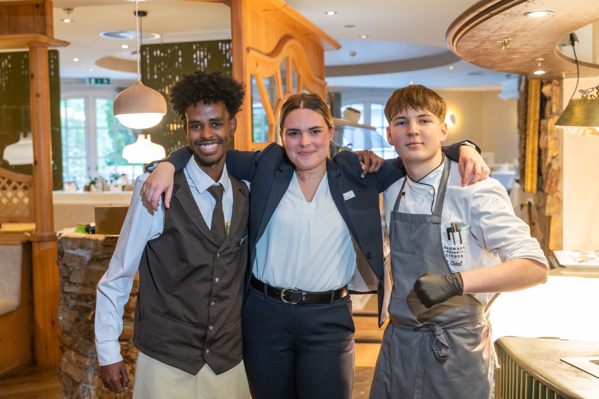 Drei Personen posieren in einem Restaurant für ein Foto.