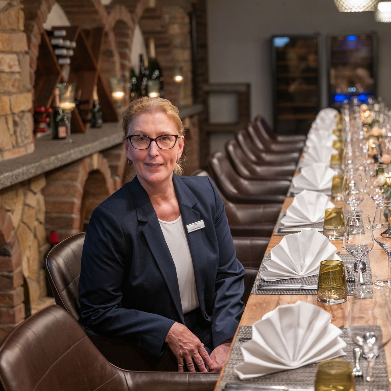 Eine Frau sitzt an einem langen Tisch in einem Restaurant.