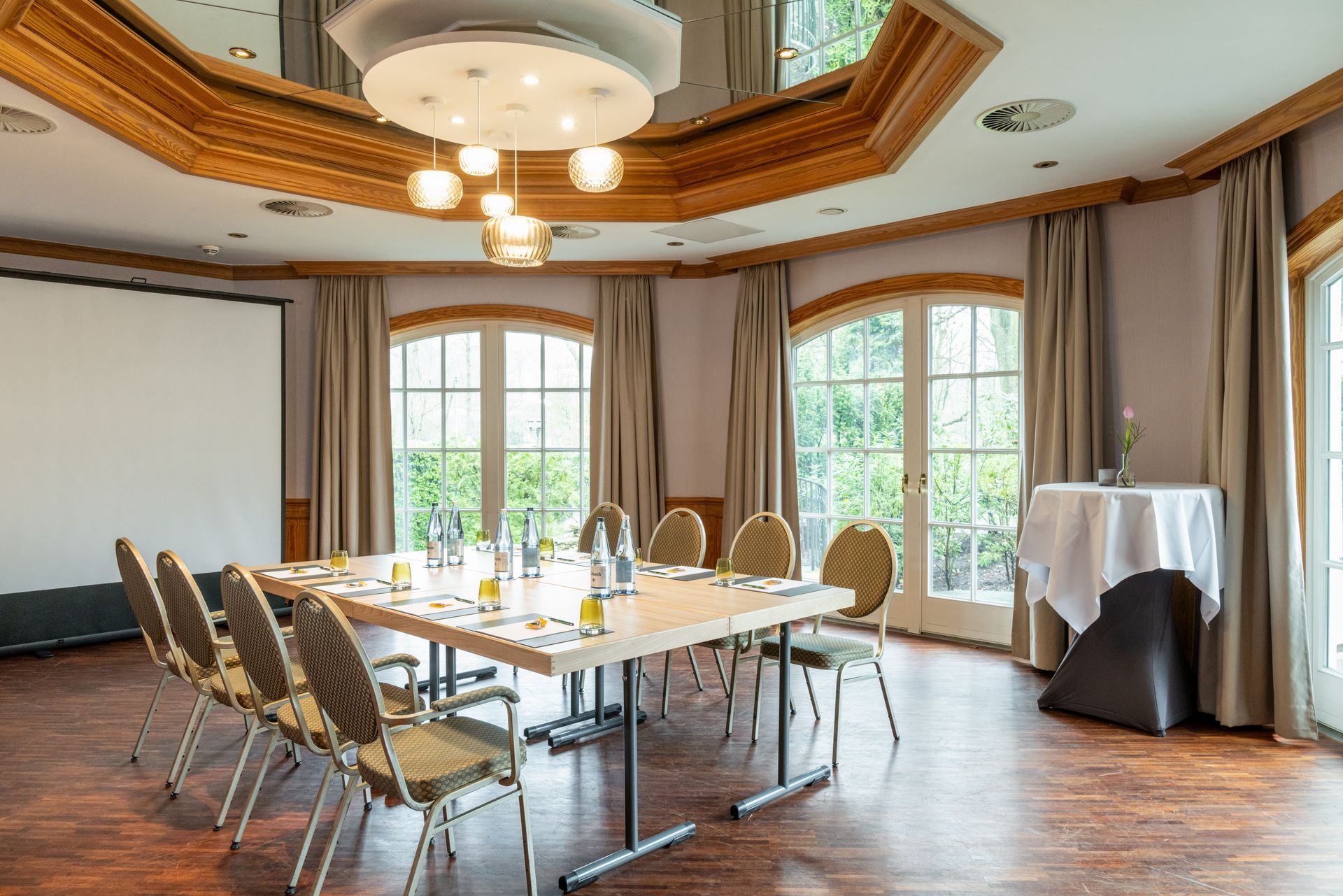 Ein Konferenzraum mit einem langen Tisch und Stühlen sowie einer Projektionsleinwand.