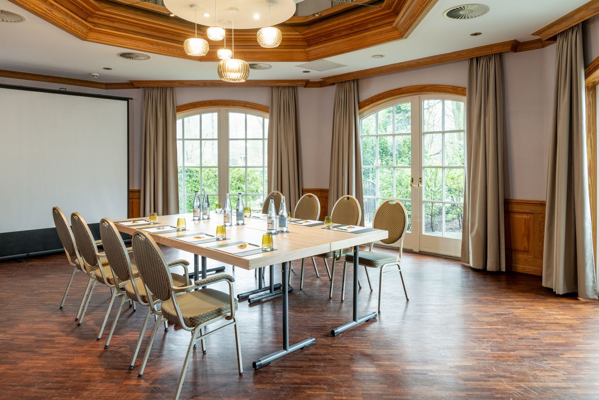 Ein Konferenzraum mit einem langen Tisch und Stühlen sowie einer Projektionsleinwand.