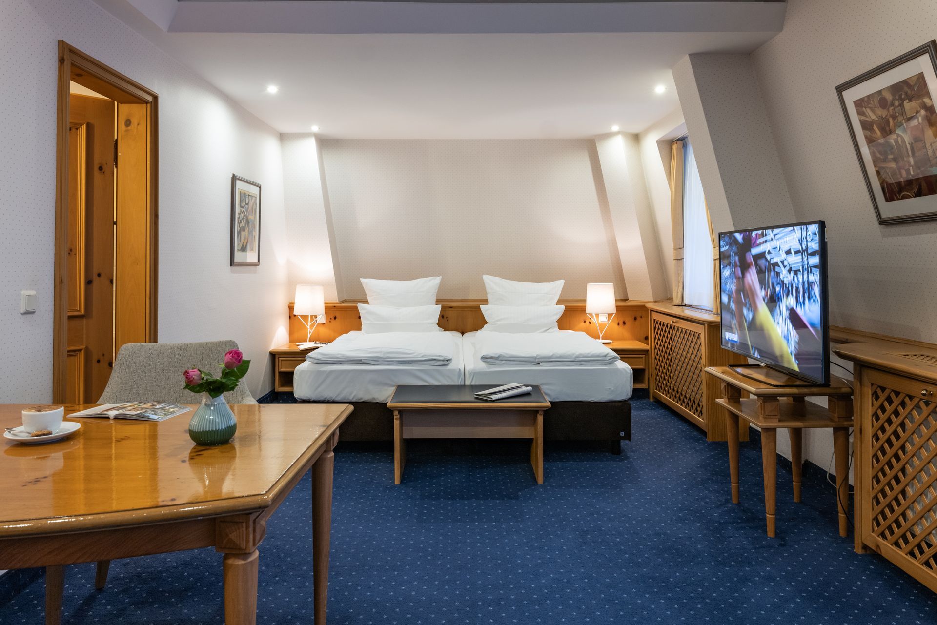 Ein Hotelzimmer mit zwei Betten, einem Tisch und einem Fernseher.