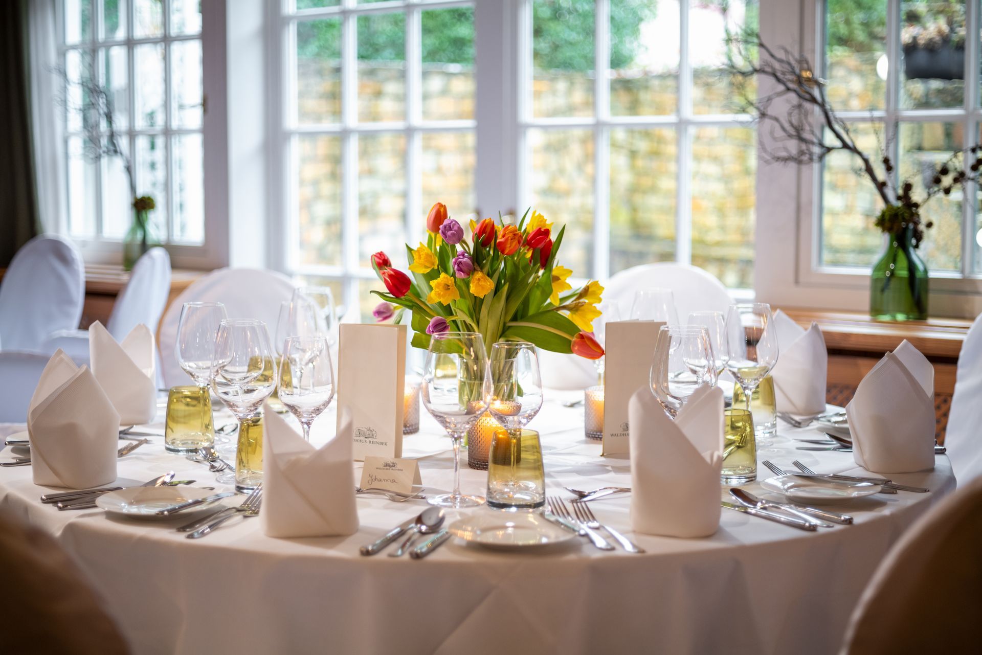 Ein für einen Hochzeitsempfang gedeckter Tisch mit einer Vase mit Blumen darauf.