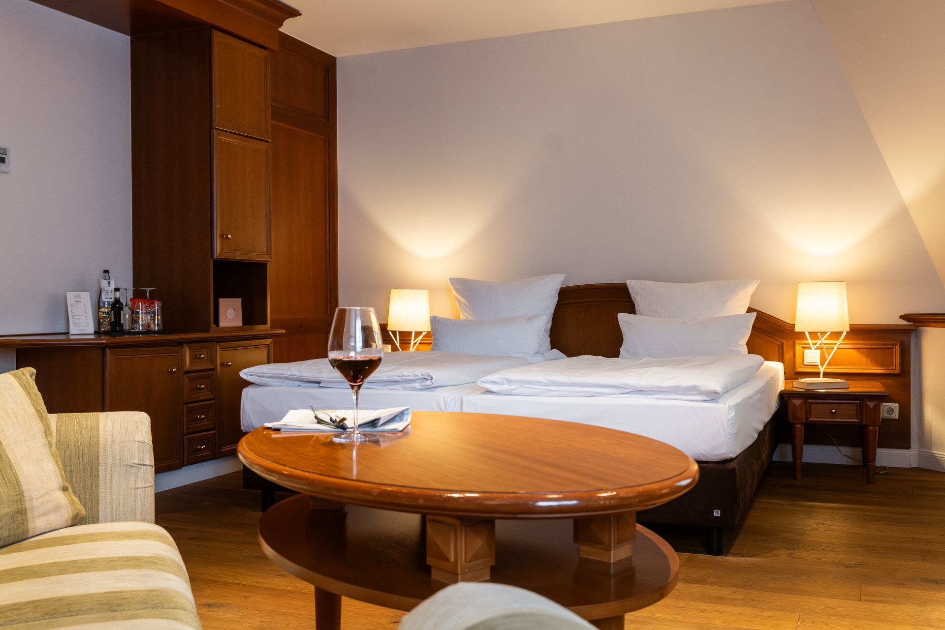 Ein Hotelzimmer mit einem Bett und einem Tisch mit einem Glas Wein darauf.