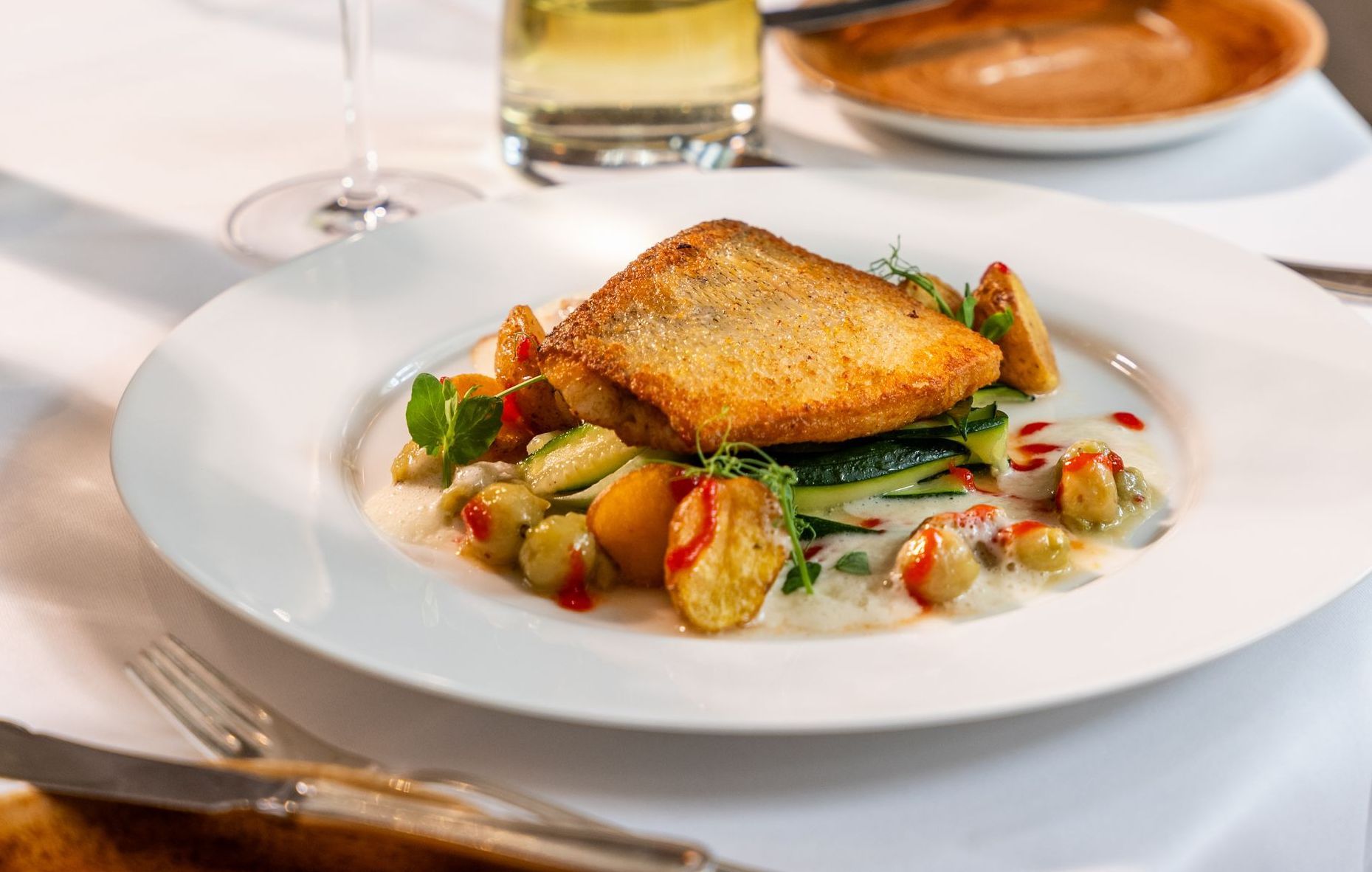 Ein weißer Teller mit einem Stück Fleisch und Gemüse auf einem Tisch.