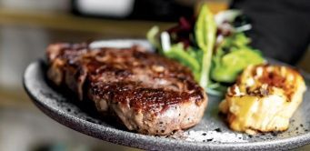 Eine Nahaufnahme eines Tellers mit Fleisch und Gemüse auf einem Tisch.