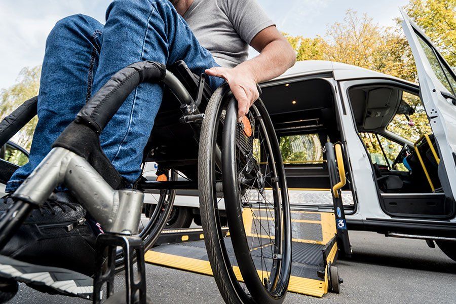 Une personne en fauteuil roulant devant une voiture