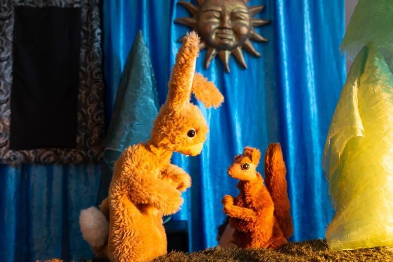Zwei Stofftiere, ein Kaninchen und ein Eichhörnchen, stehen nebeneinander auf einer Bühne.