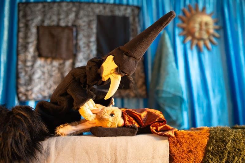 Eine Puppe liegt auf einem Bett mit einem blauen Vorhang dahinter