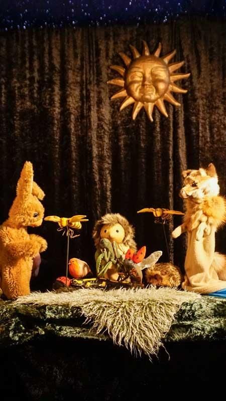 Eine Gruppe Stofftiere sitzt auf einem Tisch unter einer Sonne.