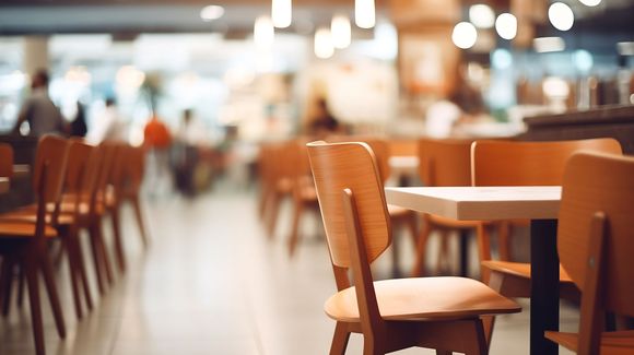 Café vide avec chaises et tables en bois dans un intérieur chaleureux et tamisé.