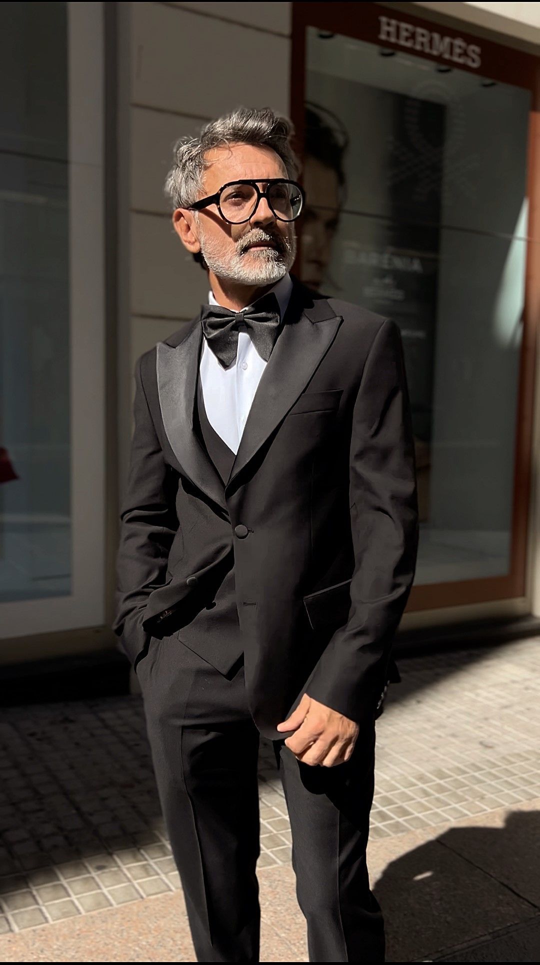 Un hombre con traje y corbata está parado frente a un edificio.