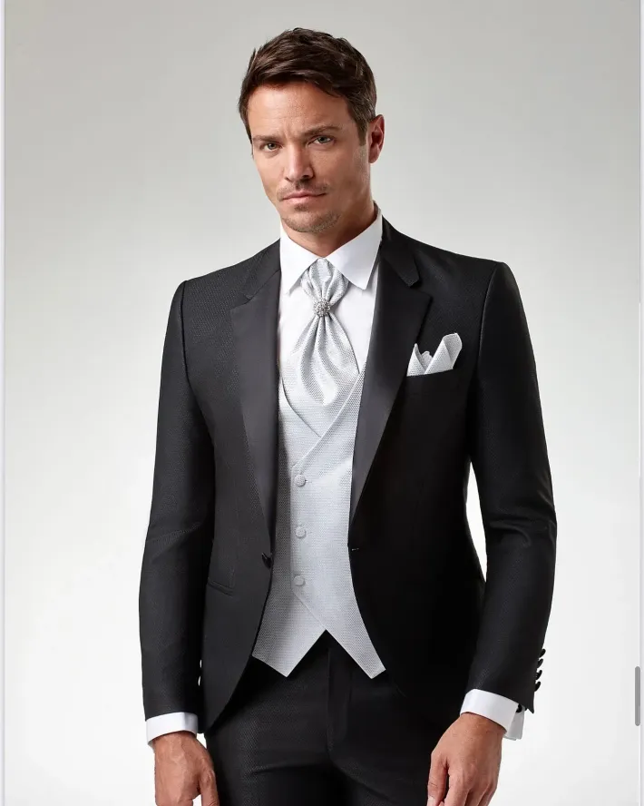 Un hombre con un esmoquin negro, chaleco blanco y corbata.