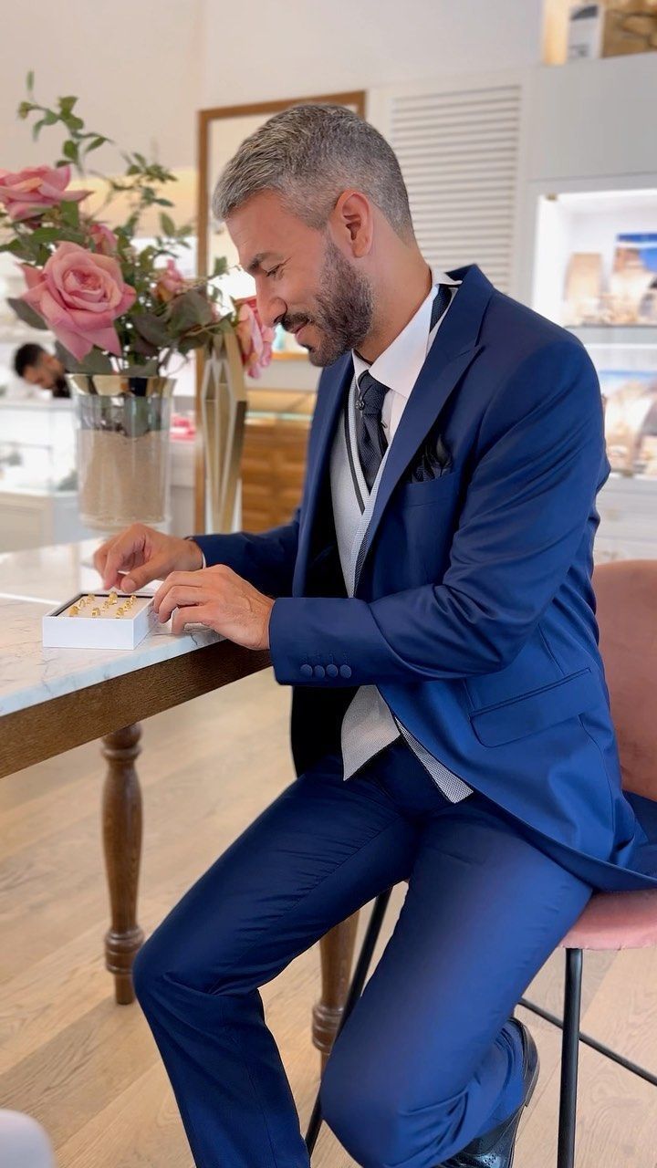 Un hombre con traje azul y corbata está sentado en una mesa.