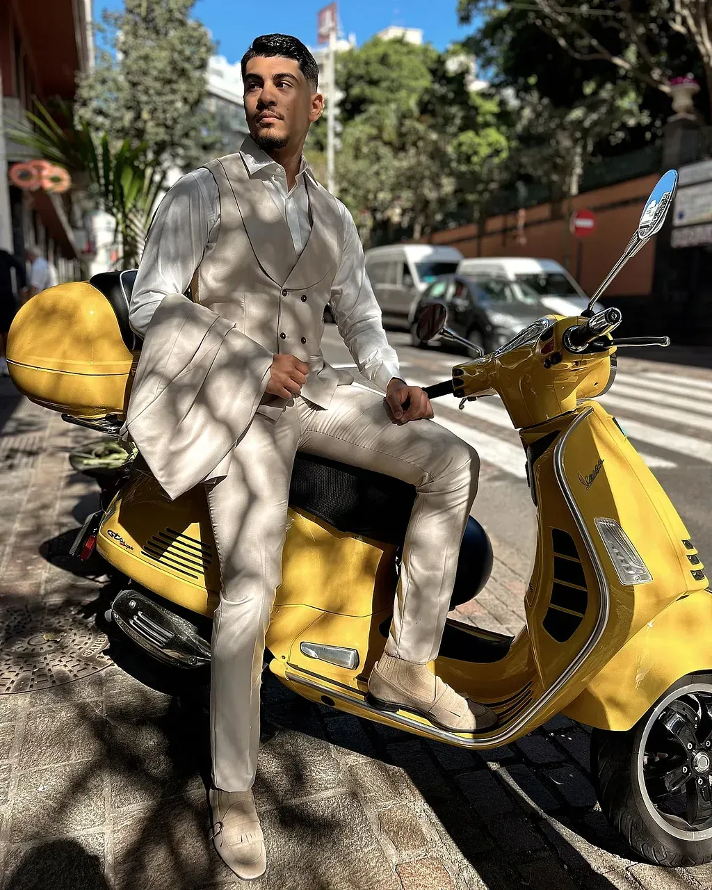 Un hombre con traje está sentado en un scooter amarillo.