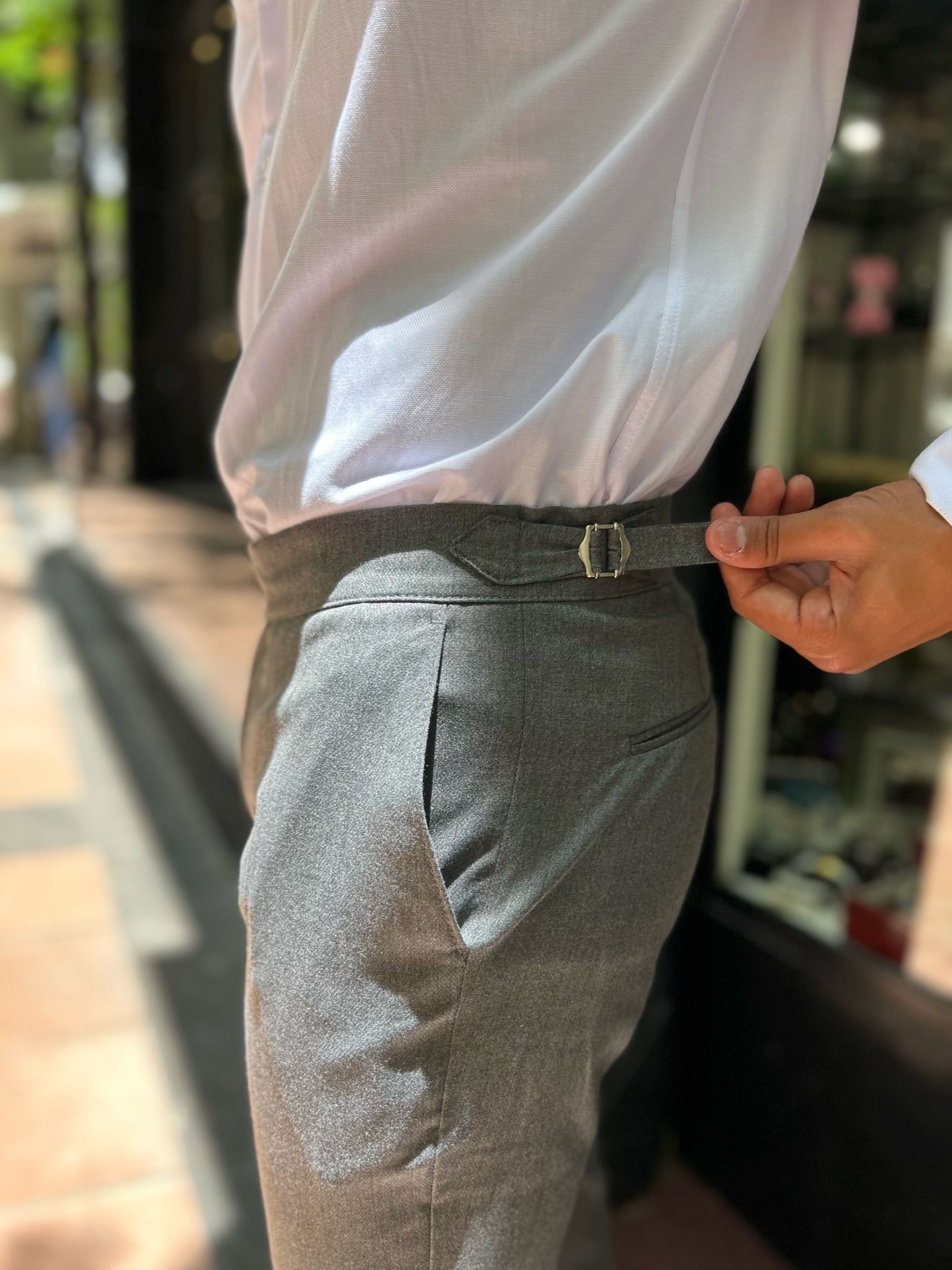 Un hombre que lleva pantalones azules y zapatos rojos está parado en una acera.