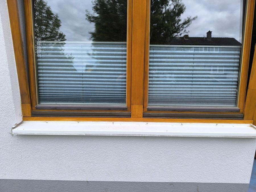 Ein Fenster mit Jalousien ist an einer weißen Wand