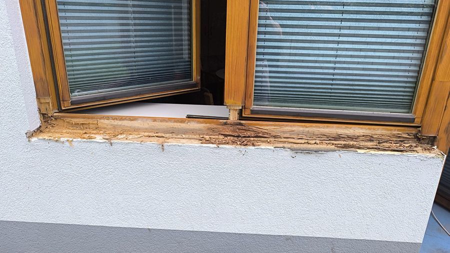 Ein Holzfenster mit Jalousien an einer weißen Wand