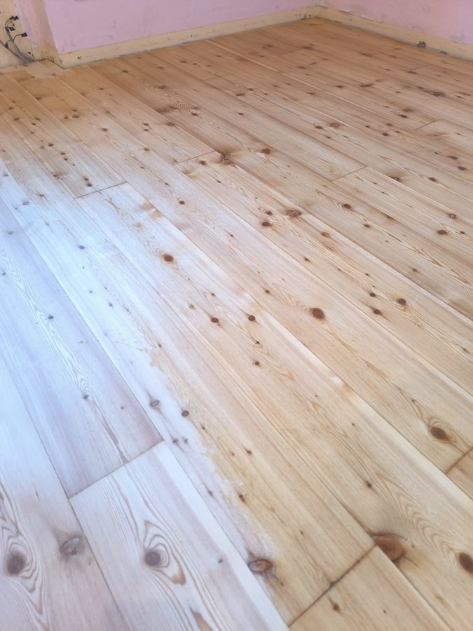 Holzdielen, helle Holzfarbe, in einem Raum mit rosa Wänden.