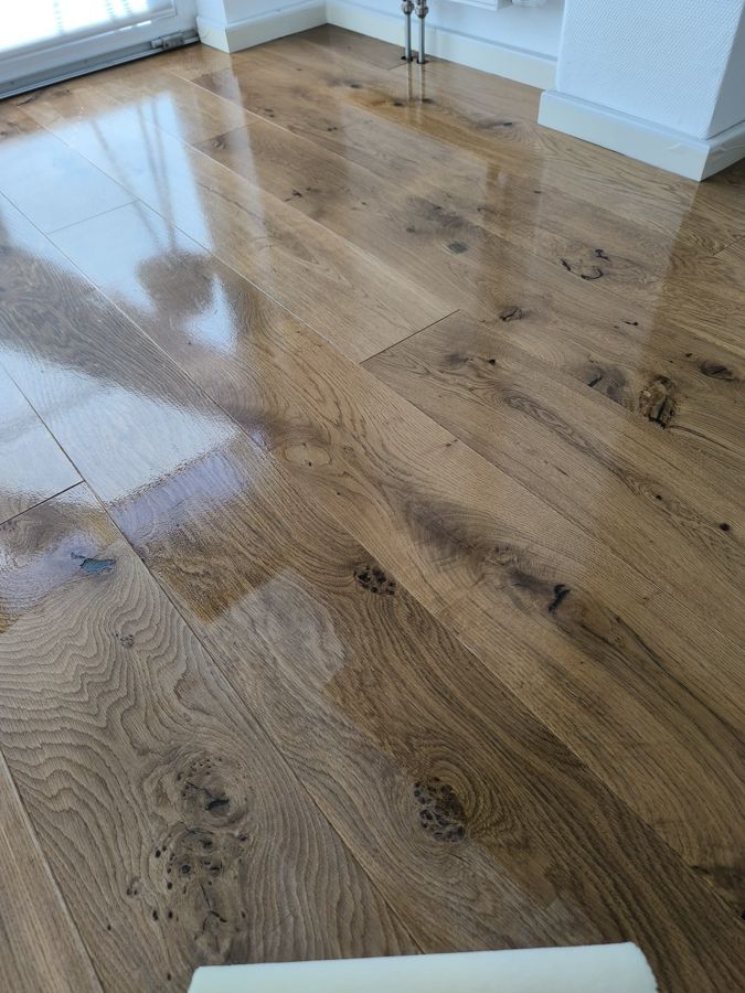 Glänzender, hellbrauner Hartholzboden in einem hellen Raum, der Licht und Details seiner Maserung reflektiert.