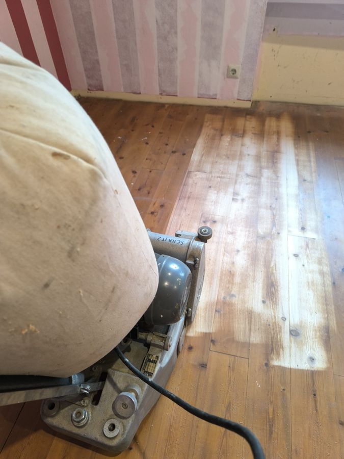 Bodenschleifer im Einsatz, um alte Oberflächen von einem Holzboden zu entfernen.