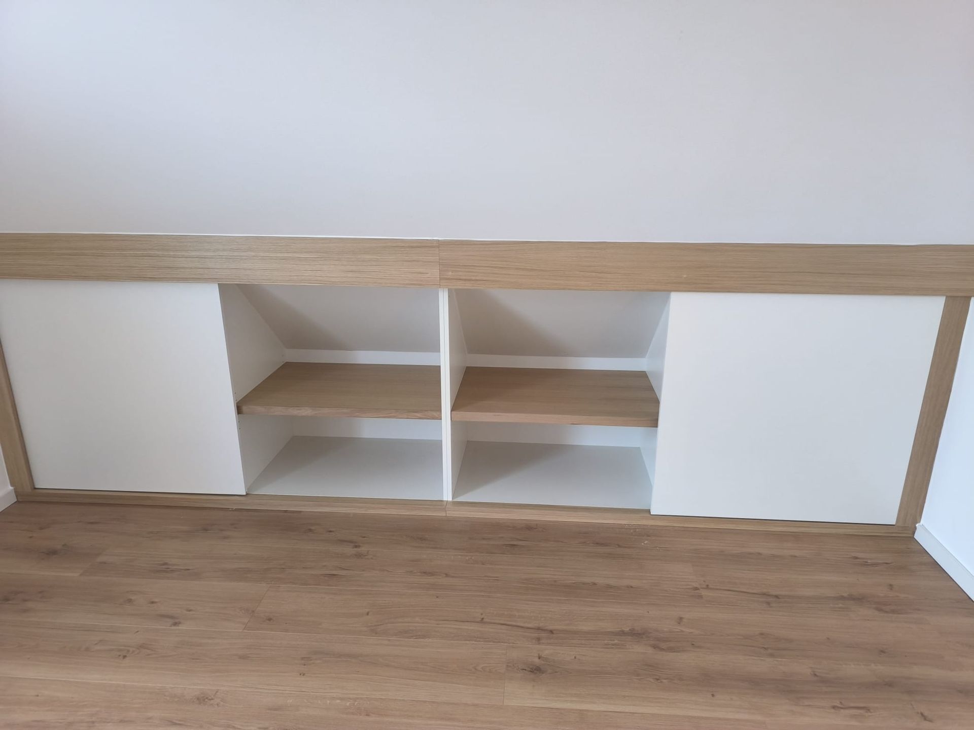 Einbauschrank mit weißen Türen und Regalen, braunen Holzverkleidungen und Boden.