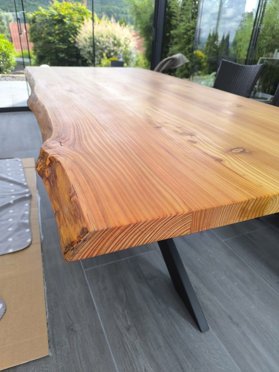 Auf einem gefliesten Boden steht ein Holztisch mit Metallgestell.