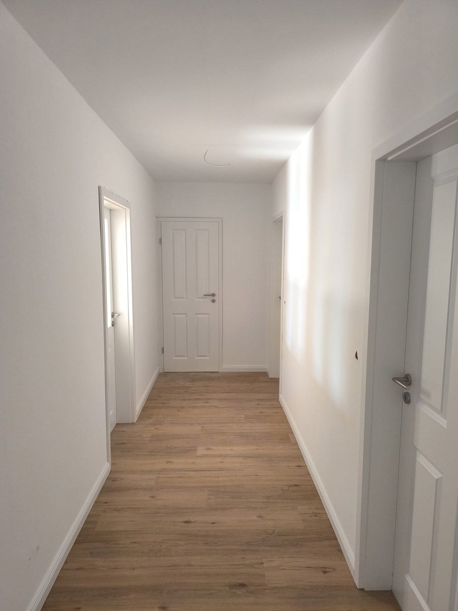 Ein langer Flur mit weißen Wänden und Holzböden