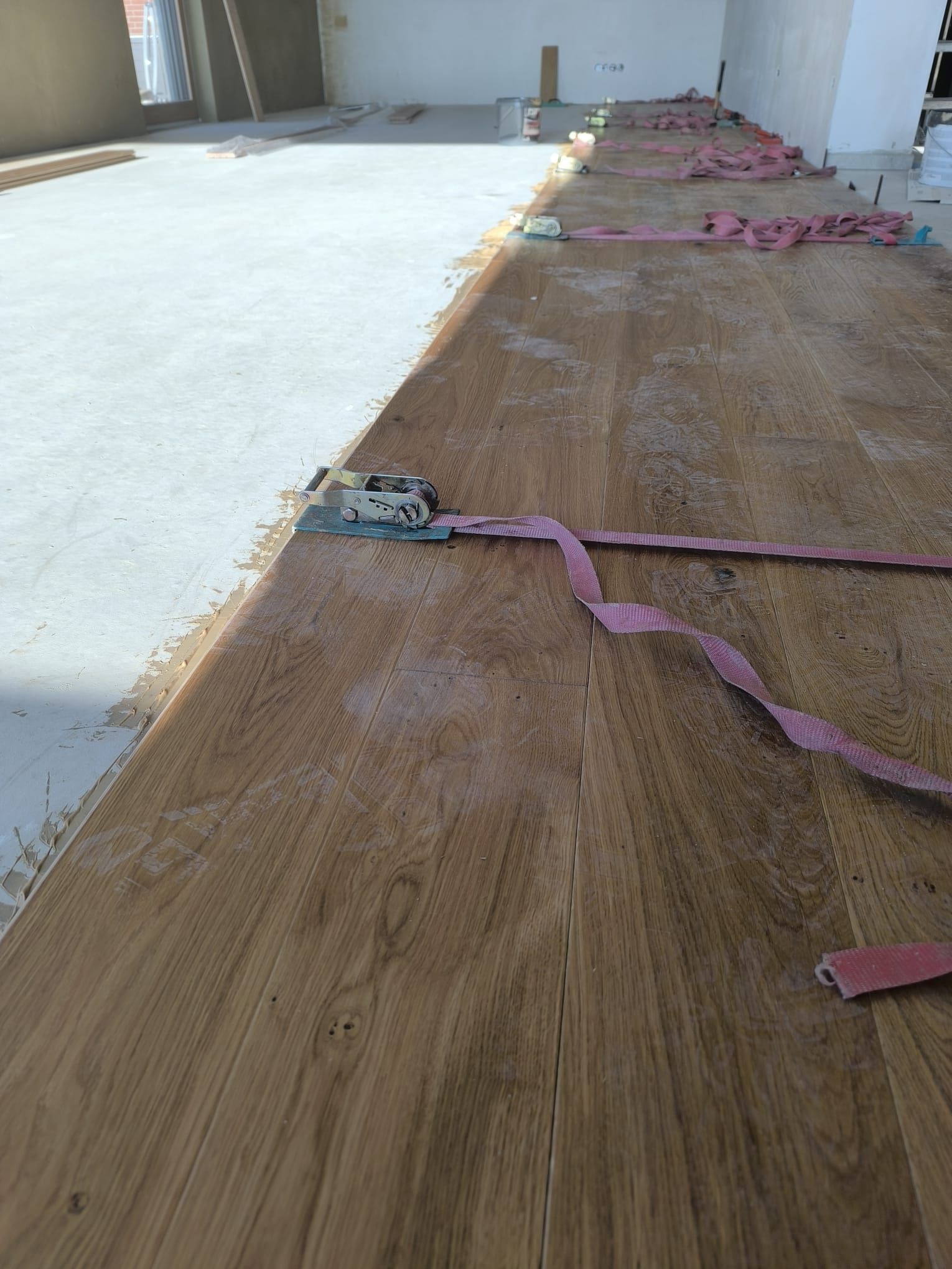 Ein Holzboden mit einem rosa Riemen darauf.