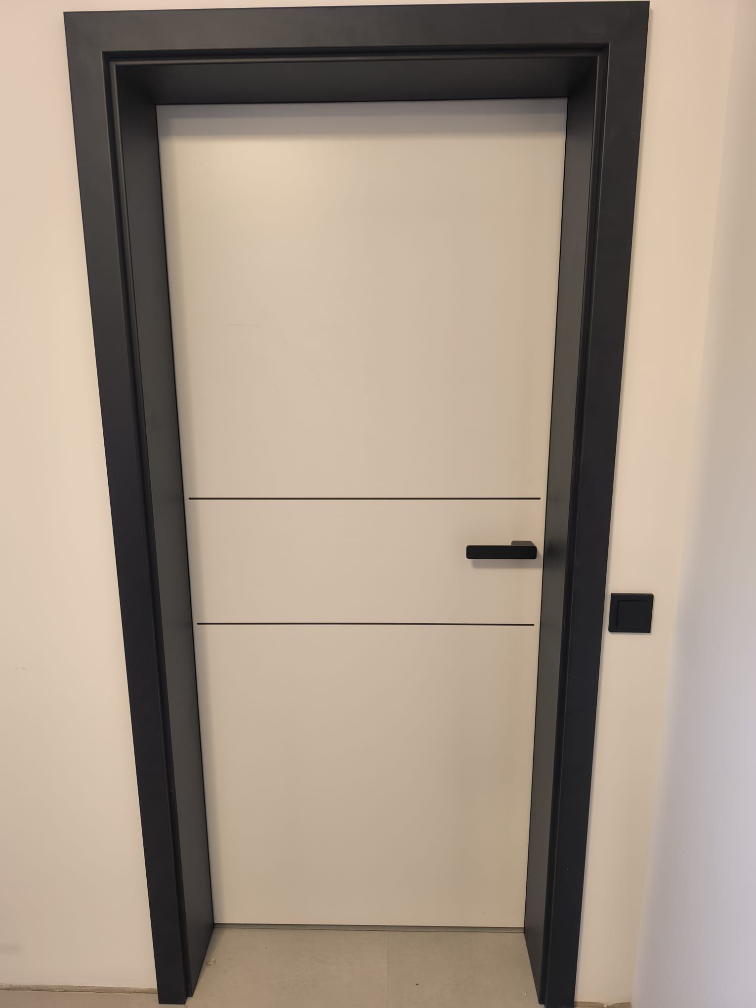 Eine weiße Tür mit schwarzem Rahmen und Griff