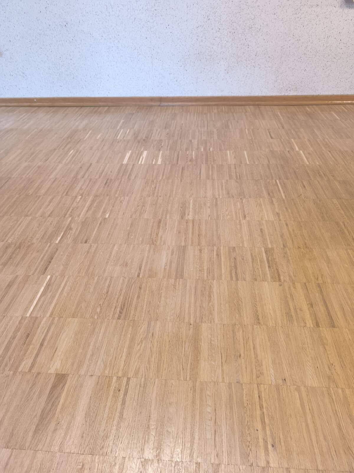 Ein Holzboden in einem leeren Raum mit einer weißen Wand.