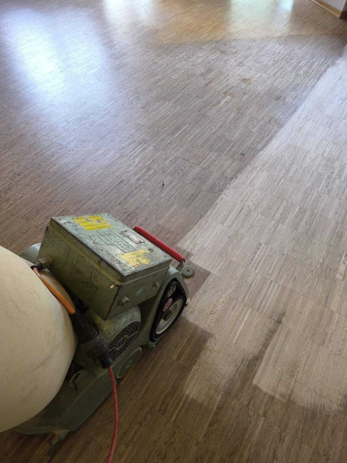 Eine Maschine schleift einen Holzboden in einem Raum.