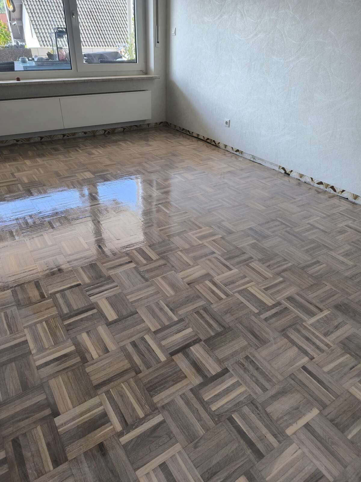 Ein Raum mit Holzboden und Fenster.