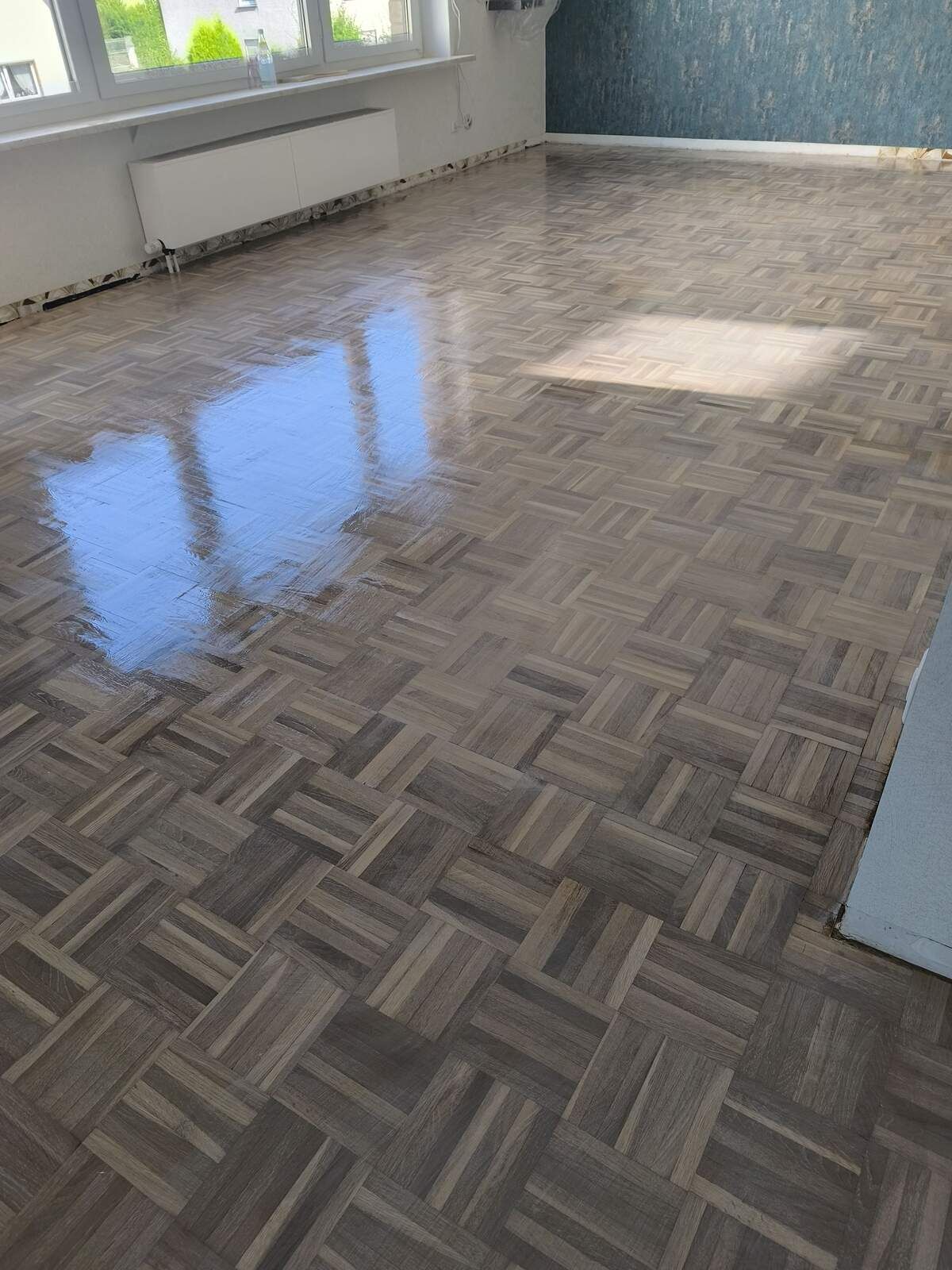 Ein Wohnzimmer mit Holzboden und Fenster.