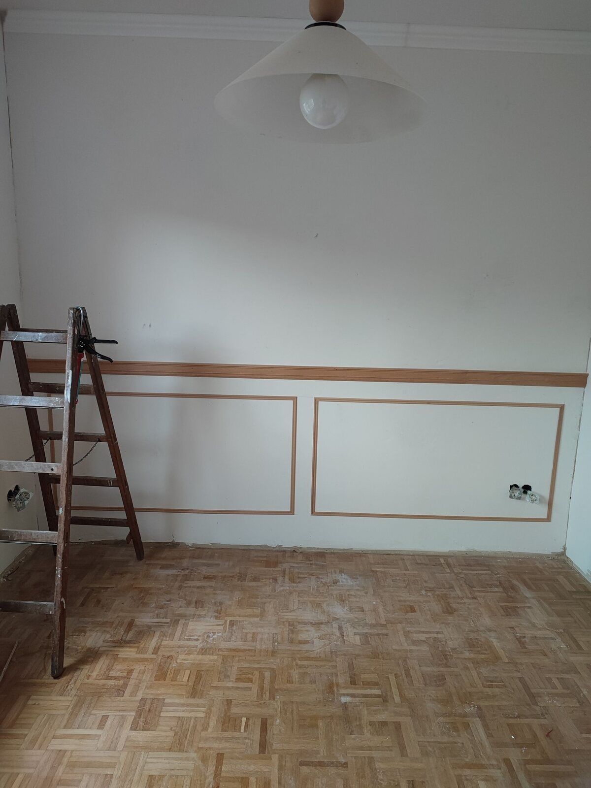 Ein leerer Raum mit Holzboden und einer Leiter.