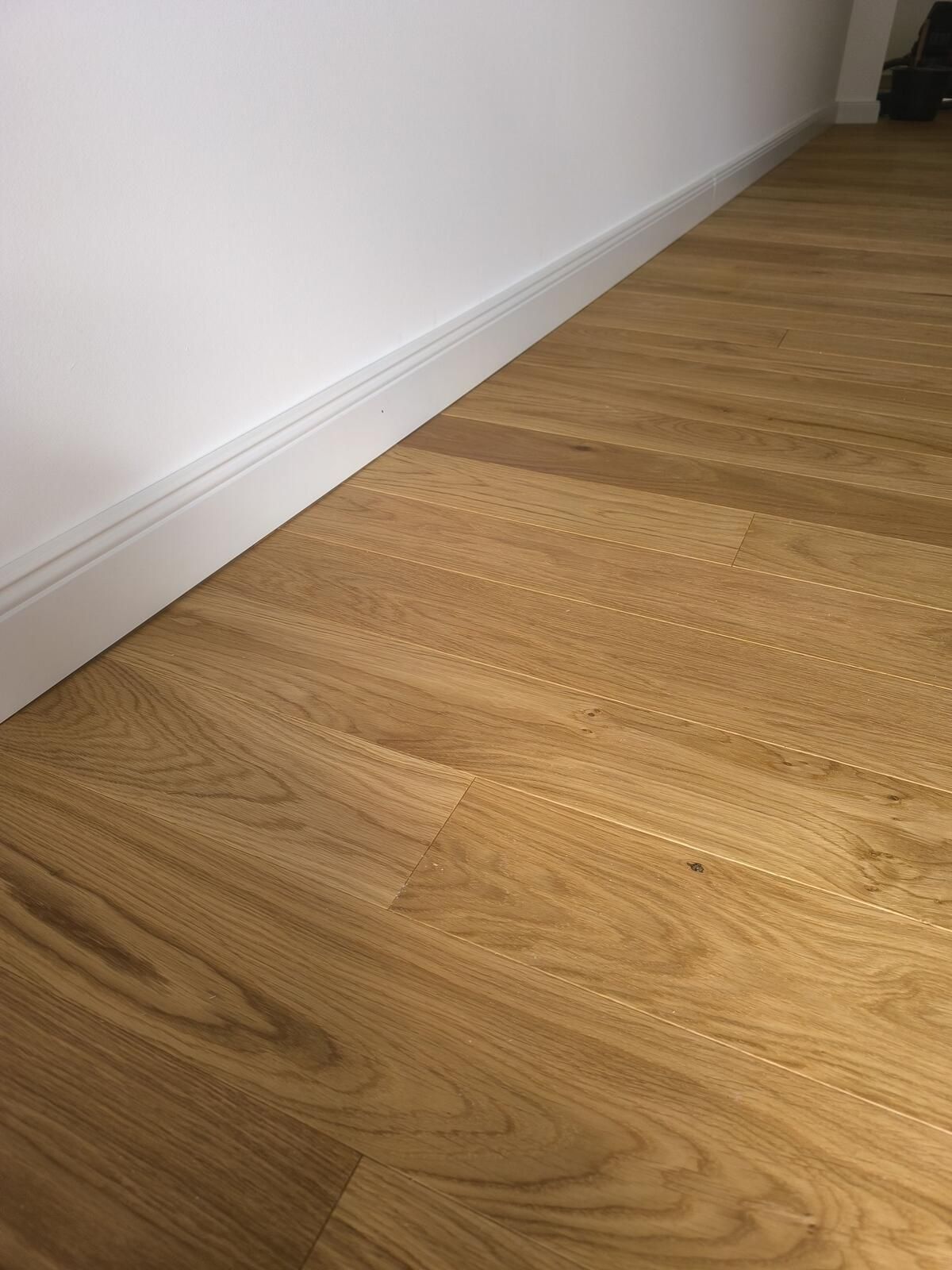 Eine Nahaufnahme eines Holzbodens mit einer weißen Wand im Hintergrund.